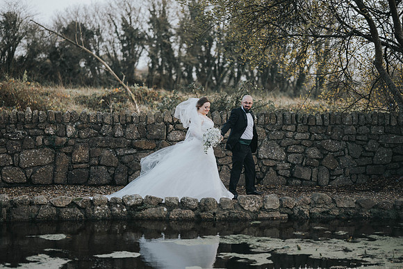 Bride and groom walking hand in hand in hotel gardens