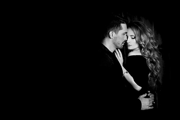 Beautiful couple in love hugging against black background. Studio black and white portrait photo of a girl blondes and a guy with short hair. Valentine's day. Loving married couple. Family happiness
